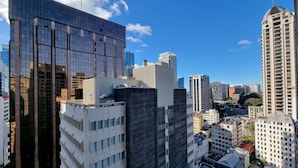 A high-rise building with a modern glass facade, surrounded by other tall buildings in a dense urban area. - Chic CBD Studio-Aircon-Wifi -Heated Pool (Auckland)