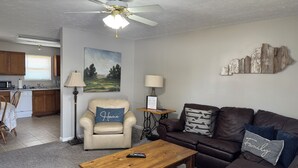 A living room with a ceiling fan, a painting, a lamp, a couch, and a coffee table.