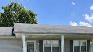 A single-story building with a covered porch, two chairs, and a small table.
