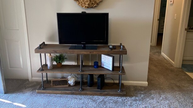 A home entertainment setup with a flat-screen TV on a wooden stand, a decorative wreath, and a welcome sign.