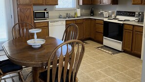 A compact kitchen with wooden cabinets, a microwave, a stove, and a dining table with chairs.