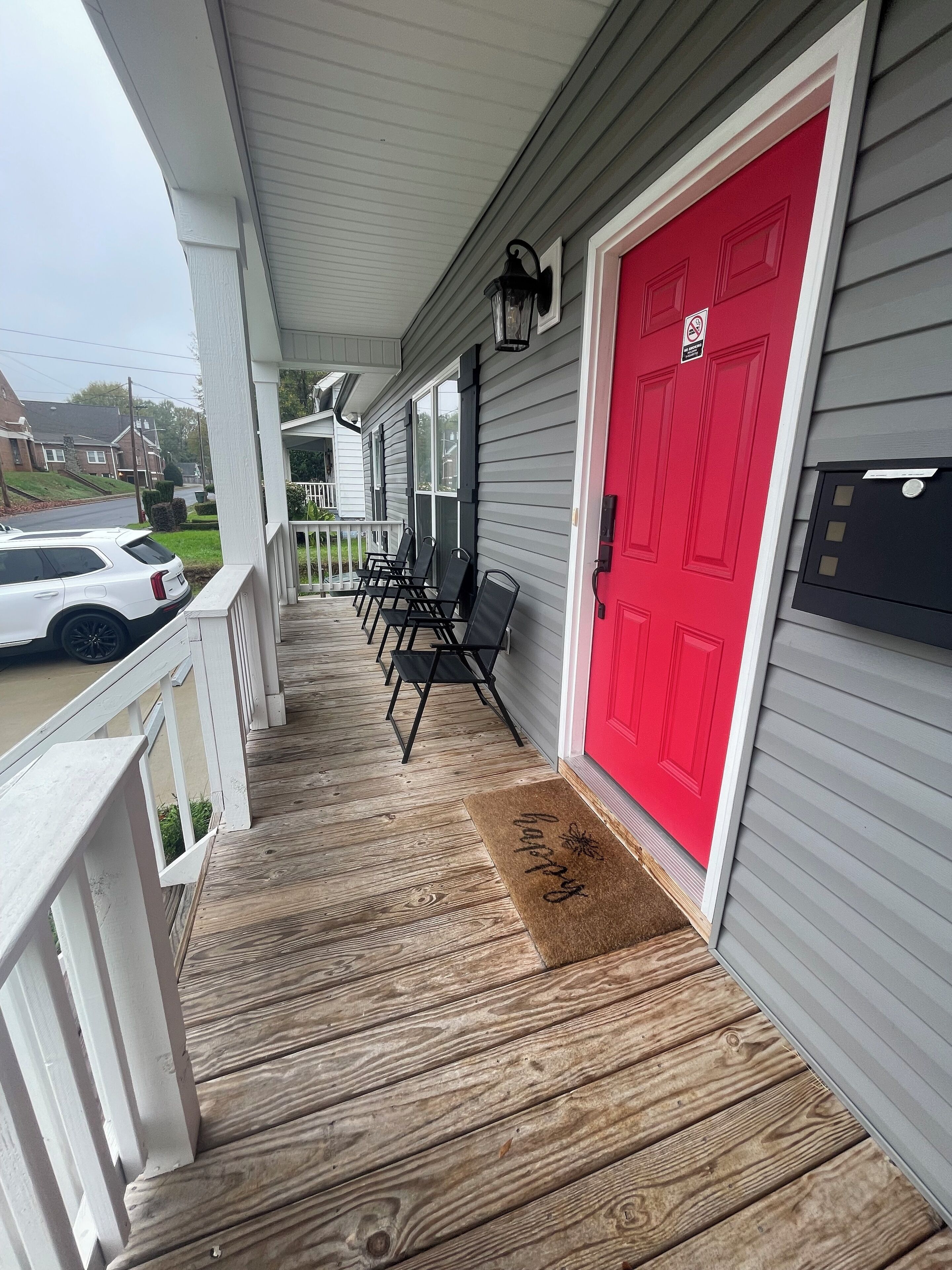 A covered porch with a red door, a bench, and a mailbox.