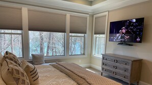 A bedroom with a large bed, multiple windows, a television, and a dresser. - Luxury Lake Lanier Estate + Double Dock (Gainesville)