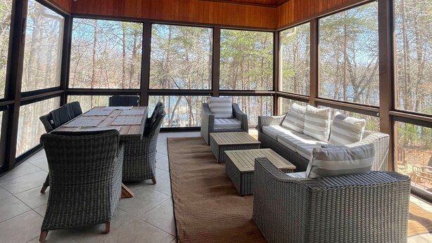 A spacious covered patio with wicker furniture, large windows, and a ceiling fan. - Luxury Lake Lanier Estate + Double Dock (Gainesville)