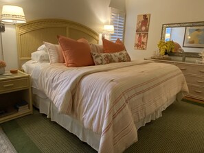 A neatly arranged bedroom with a large bed, two bedside tables, a dresser, and a mirror.
