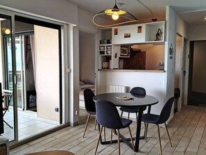 A modern dining area with a round table and four chairs, a pendant light, and a view through a glass door to an outdoor space. - Fall in love with this cosy one-bedroom flat with stunning sea views - 4GSUD101 (CANET PLAGE)