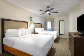 Two single beds with white linens and a flat-screen TV on a dresser.