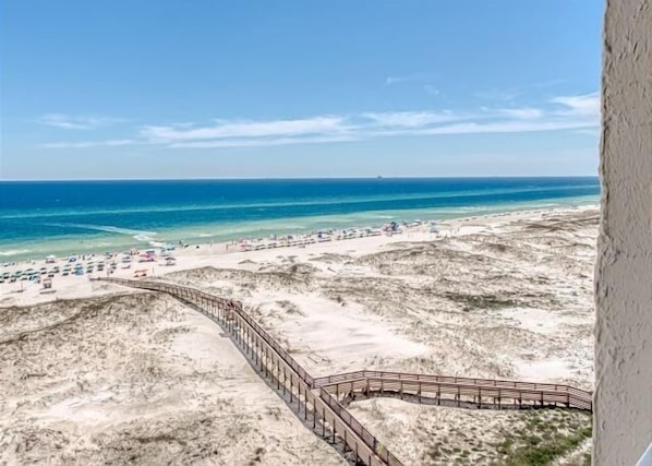 Walk along the beach on a scenic boardwalk, surrounded by umbrellas and the soothing sound of the ocean.