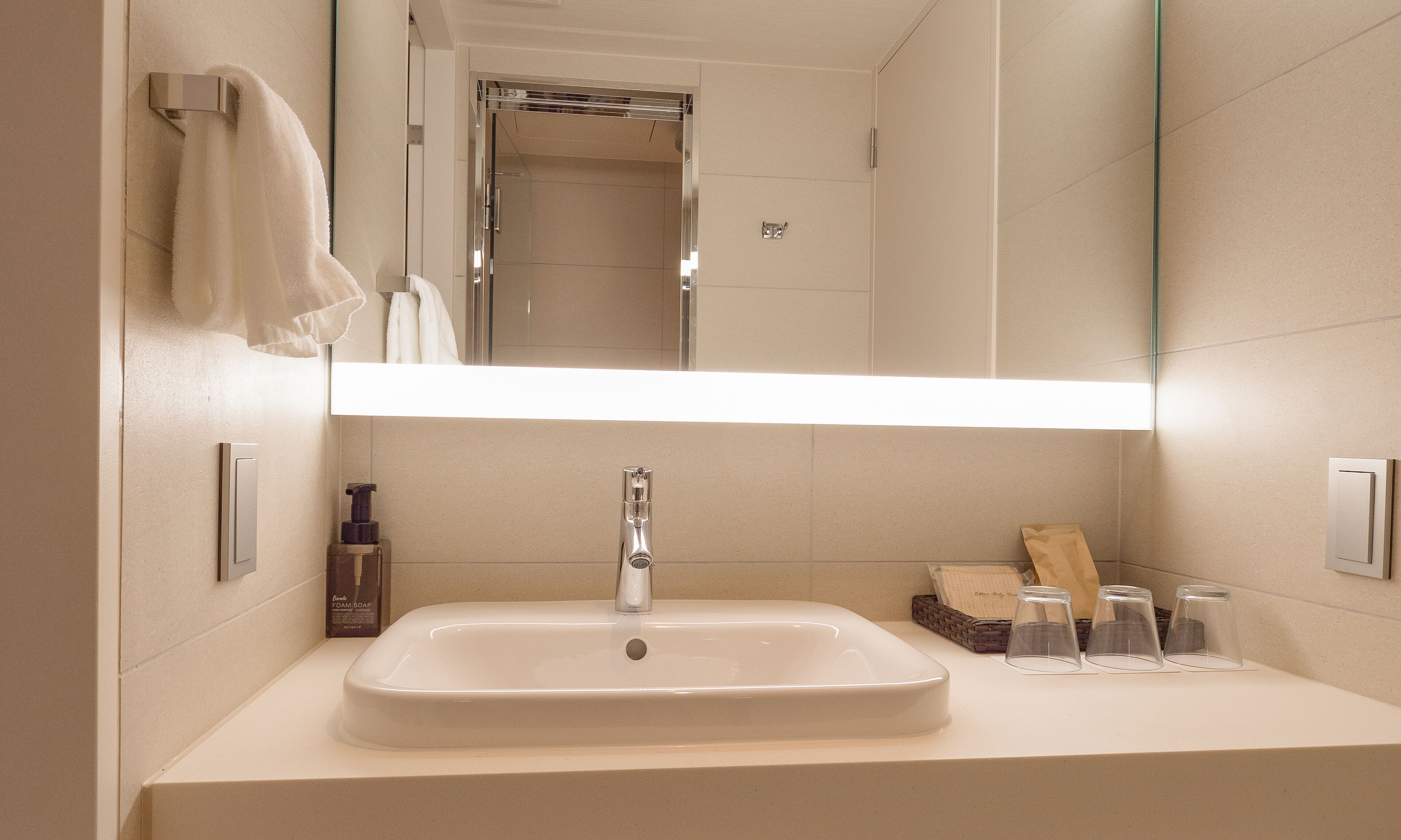 A bathroom with a large mirror, a sink, and a shower.