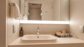 A bathroom with a large mirror, a sink, and a shower.