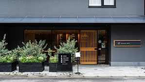 A modern building with a black awning, a wooden door, and a signboard listing amenities like coffee, craft beer, hamburger, and grill. - HOTEL RINGS KYOTO (Kyoto)