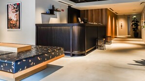 A modern hotel lobby with a reception desk, seating area, and a hallway leading to other rooms. - HOTEL RINGS KYOTO (Kyoto)