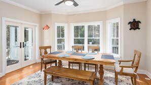 Une salle à manger avec une table en bois, six chaises et un ventilateur de plafond.
