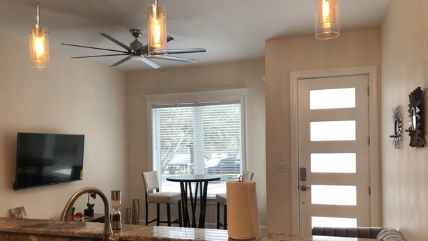 A modern kitchen with granite countertops, a built-in sink, a ceiling fan, and pendant lighting. - Newly constructed modern home with luxurious rooftop patio (Tallahassee)