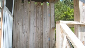 A wooden deck with a white railing and a wooden door. - Island Cat: This spacious and comfortable island home (Ocracoke)