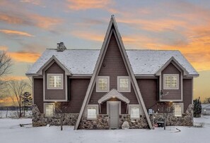 A two-story house with a symmetrical facade, a central entrance, and a stone foundation.