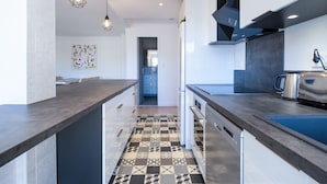A modern kitchen with dark countertops, a patterned backsplash, and pendant lighting. - 2Br. Apartment, 100m from Beaches, Terrace & Parking (Cannes)