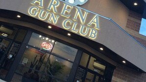 The exterior of the Arena Gun Club with a prominent sign and a large circular logo above the entrance. - Motel 9 (Laredo)