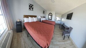 A hotel room with a large bed, a desk, a chair, a mirror, and a window with curtains. - Motel 9 (Laredo)