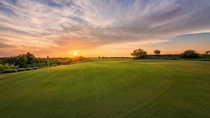 A golf course at sunset with a clear sky and distant trees. - Motel 9 (Laredo)