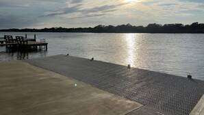 Un muelle frente al agua con una plataforma de hormigón y una barandilla de metal.