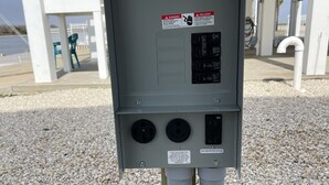 Caja eléctrica con etiquetas de advertencia, dos interruptores y un enchufe con protección GFCI.