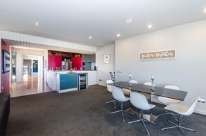 A modern kitchen with a red accent wall, a dining area with a glass table and white chairs, and a "Better together" sign on the wall.