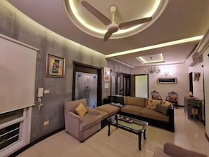Ein modernes Wohnzimmer mit Deckenventilator, einer Couch, einem Couchtisch und einer Tür mit Verzierungen.