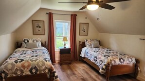 A bedroom with two wooden beds, a ceiling fan, and a window with curtains. - Best in the Bay!! 3B/1.5ba, Pet friendly Home (Alexandria Bay)