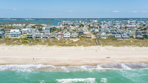 A coastal residential area with houses along the beach, a clear sky, and waves in the foreground. - Oceanfront Family Cottage: Hot Tub, Heated Pool. Game Room & Stunning Beach View (Atlantic Beach)