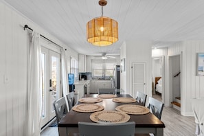 Enjoy meals in this dining area with a long table set for four, featuring woven placemats.