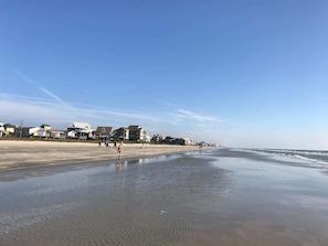 A beach with houses along the shore and a clear sky.
