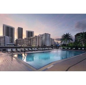 A swimming pool with lounge chairs and a cityscape in the background. - Beautiful 2 bedroom condo w/ocean views (Hallandale Beach)