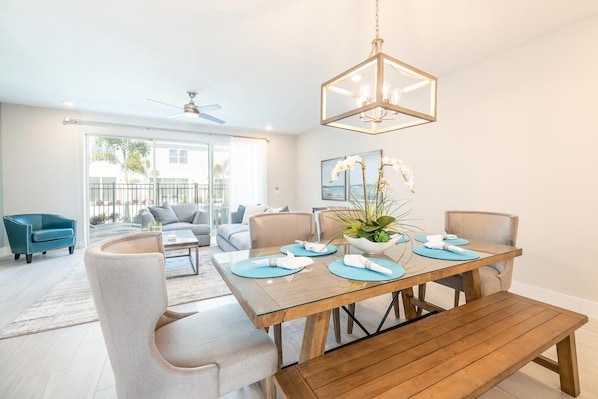 A modern dining area with a wooden table, blue placemats, and a decorative plant centerpiece.