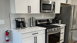 A modern kitchen with white cabinets, stainless steel appliances, and a wooden floor. - Comfortable home with sparkling private pool minutes to the Strip! (Henderson)