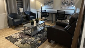A modern living room with a sofa, armchairs, a coffee table, and a dining table. There are two paintings on the wall and a window with blinds. - Comfortable home with sparkling private pool minutes to the Strip! (Henderson)