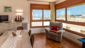 Una habitación con una mesa de comedor, una silla, un televisor y vistas al mar.