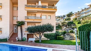 Un immeuble résidentiel à plusieurs étages doté d’une piscine, d’un escalier et d’un jardin bien entretenu.