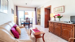 Un salon avec un canapé en cuir, un meuble en bois et un coin repas comprenant une table et des chaises.