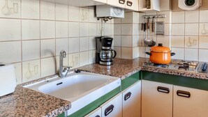 Eine Küche mit Spüle, Kaffeemaschine und einem orangefarbenen Topf auf der Arbeitsfläche.