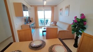 Un salon moderne avec un canapé, une table à manger avec des assiettes et un téléviseur.