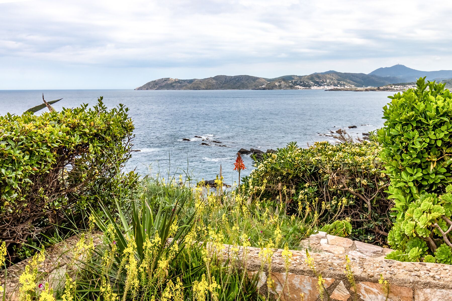 A coastal landscape with a view of the sea and distant hills.