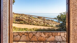 Mural de pedra com guarda de madeira, com vista para uma trilha costeira.