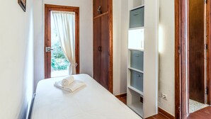 Um quarto com uma cama, um guarda-roupa e estantes embutidas.