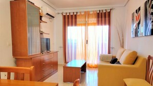 Una sala de estar con un mueble de televisión de madera, un sofá, una mesa de centro y una mesa de comedor.