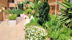 Un patio con macetas, una estatua blanca y un edificio con balcones.