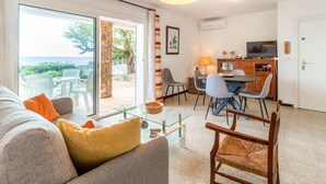 A living room with a sofa, coffee table, and a dining area with chairs and a table. - Carboneras 48 - Apartment on the seafront (Llança)