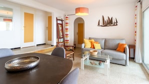 A modern living room with a grey sofa, a glass coffee table, and a dining table with chairs. - Carboneras 48 - Apartment on the seafront (Llança)