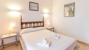 Una habitación de hotel con una cama grande, dos mesitas de noche con lámparas y dos cuadros enmarcados en las paredes.