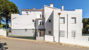 Un edificio moderno blanco con entrada protegida, varias ventanas y techo inclinado.